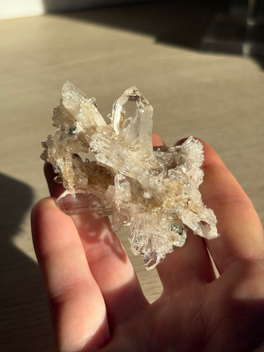Hand holding a crystal cluster against a neutral background